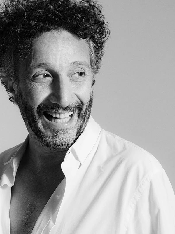 Retrato en blanco y negro de Fito Páez sonriendo, con camisa blanca
