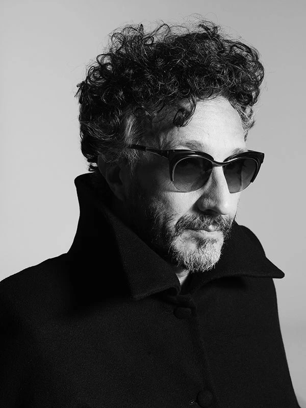 Retrato en blanco y negro de Fito Páez con anteojos oscuros y abrigo negro